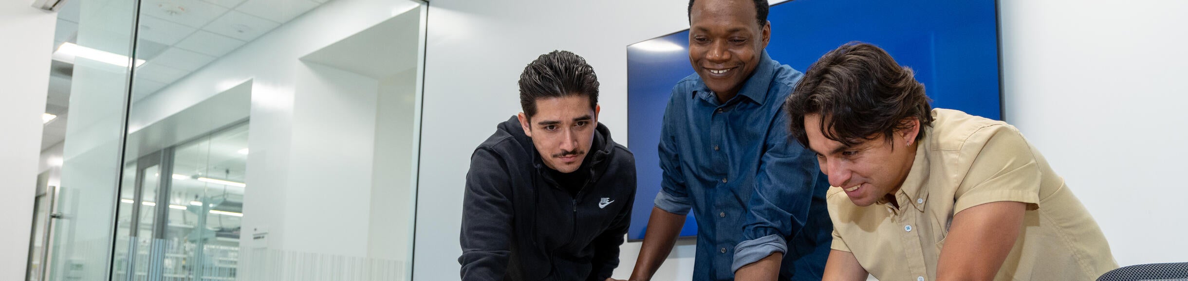 A group of startup founders gathered around a laptop talking about their science at the Life Sciences Incubator coworking space