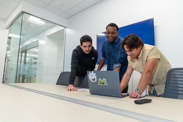 A group of startup founders gathered around a laptop talking about their science at the Life Sciences Incubator coworking space